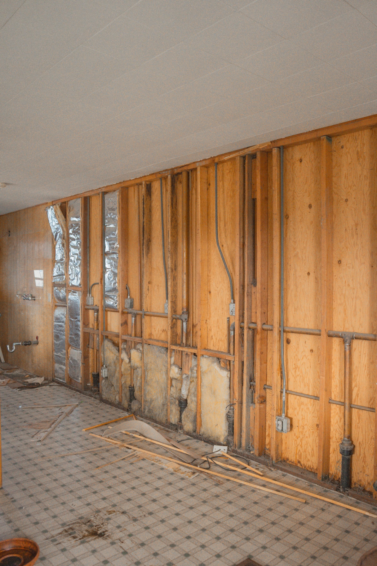 Interior remodel with wall paneling removed exposing studs and plumbing