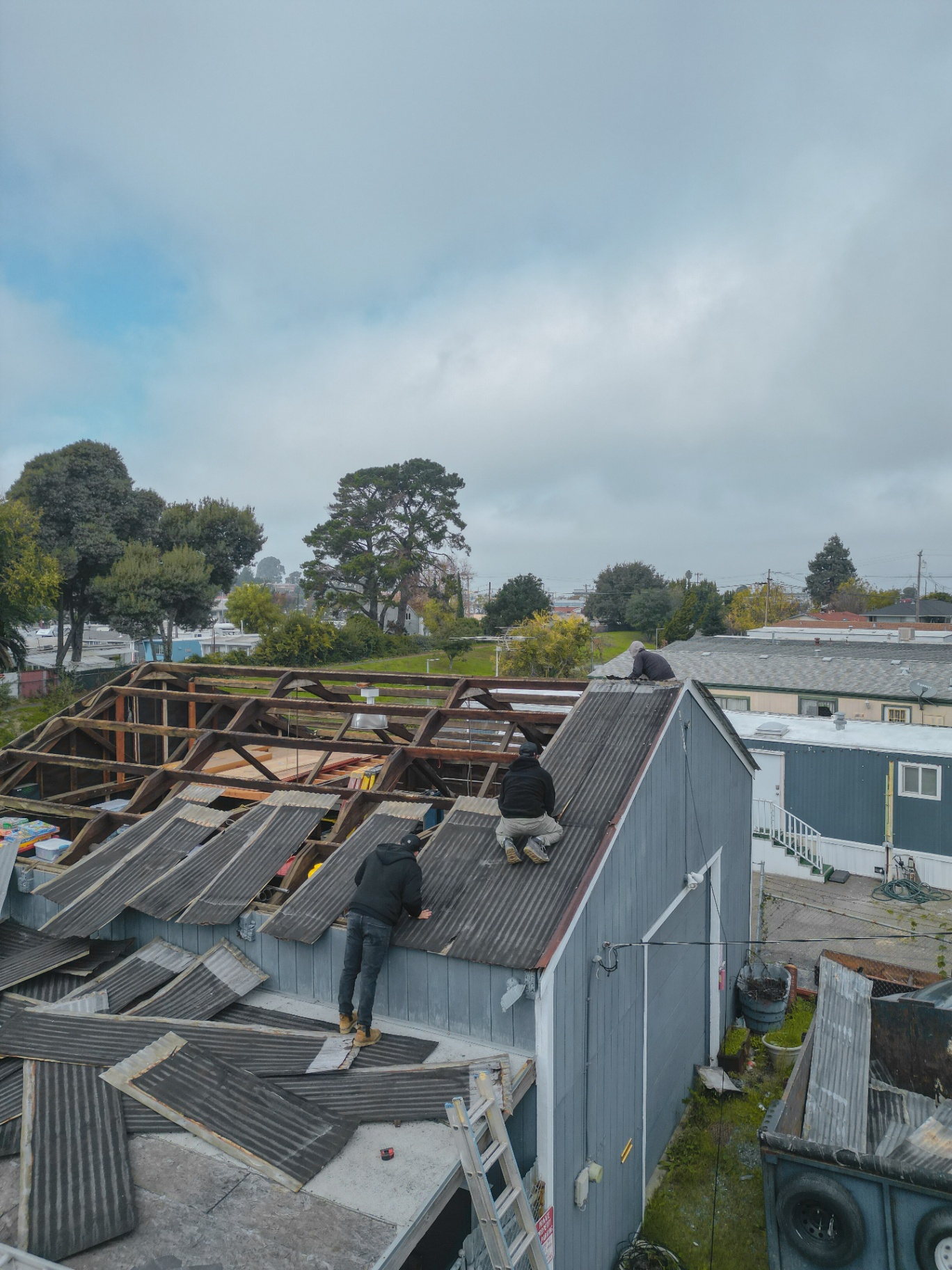 Crew removing old corrugated roofing from the shed