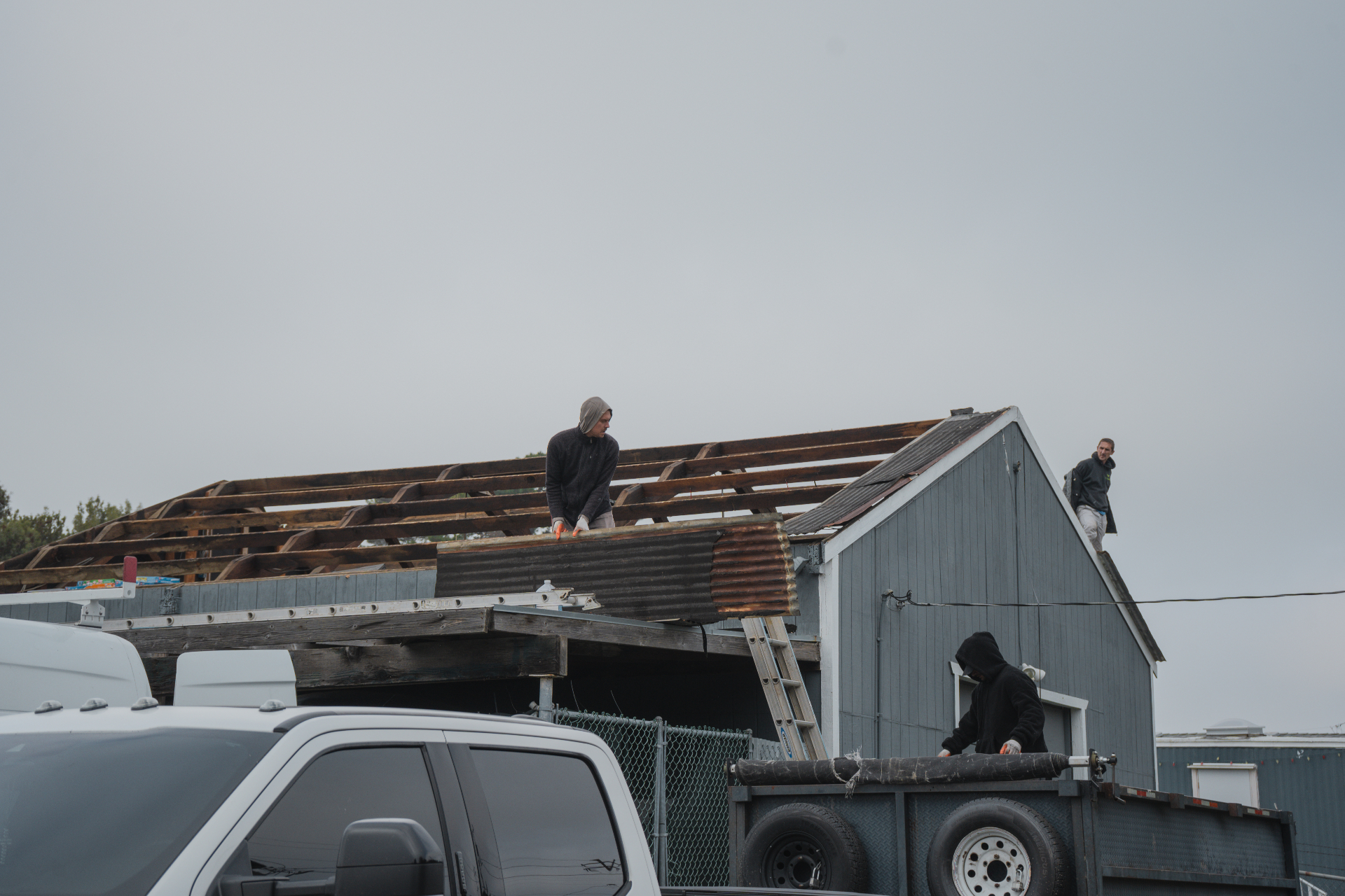 Crew removing corrugated metal panels from the shed roof