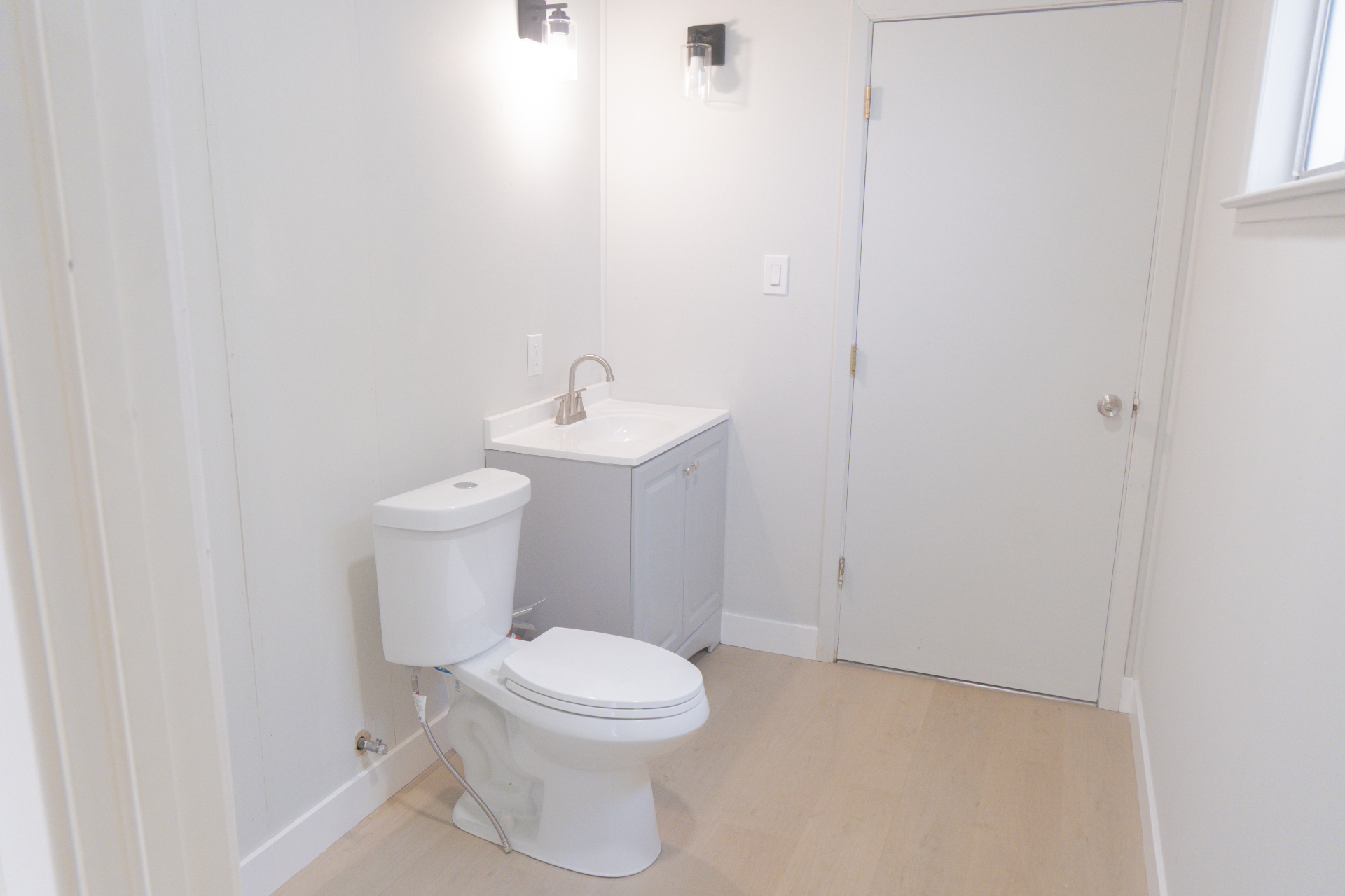 Completed bathroom with new vanity, toilet, lighting, and trim