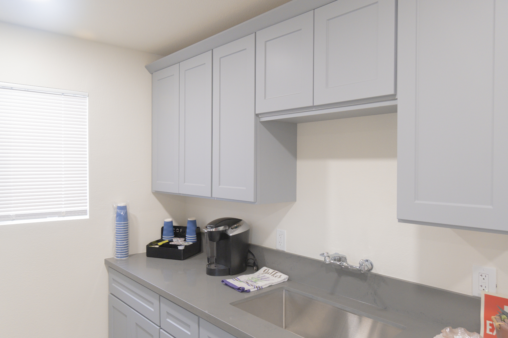 Finished kitchenette with gray cabinetry, counter, and utility sink