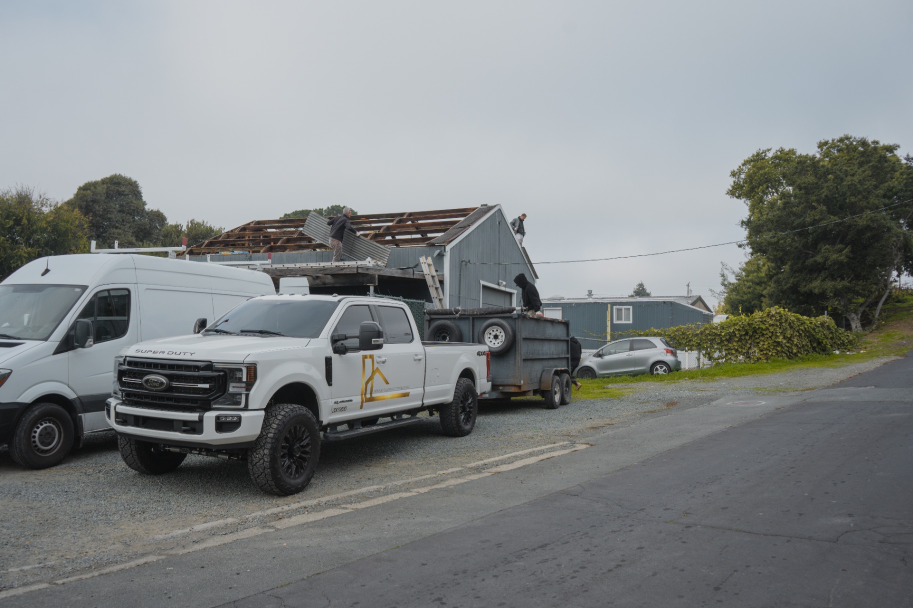 Crew truck and dump trailer staged at the shed roof tear-off