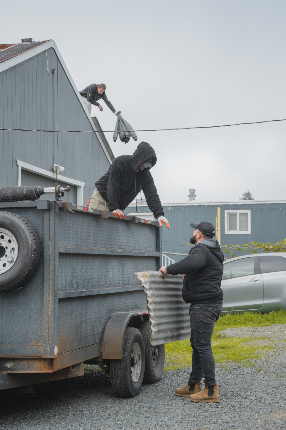 Crew loading old roofing panels into the dump trailer